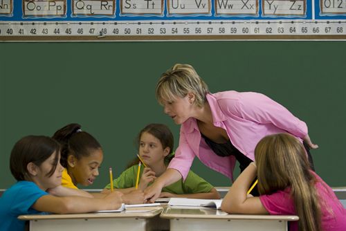 A teacher helping students with their assignments
